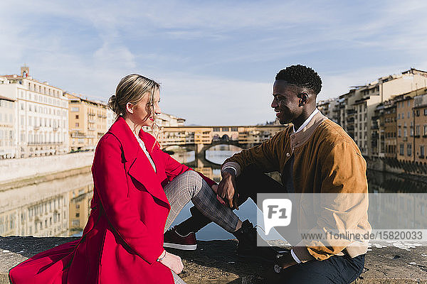 Lächelndes junges Paar sitzt auf einer Brücke in der Stadt Florenz  Italien