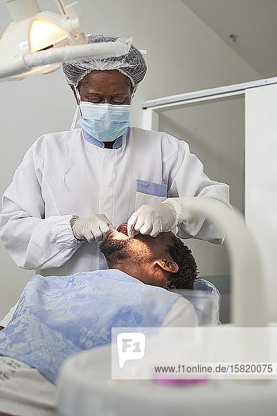 Zahnärztin untersucht Zähne eines Mannes