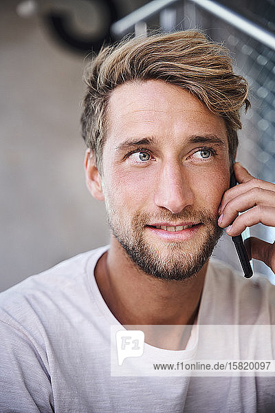 Porträt eines jungen Mannes mit T-Shirt beim Telefonieren