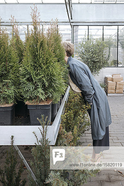 Woman hiding her head in plants in flower shop
