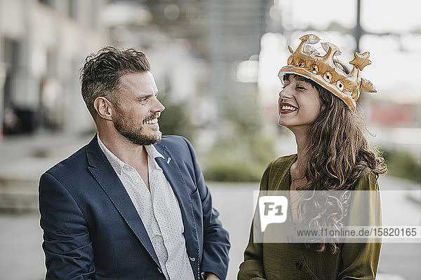 Lächelnder Geschäftsmann schaut eine Frau an  die eine Krone trägt