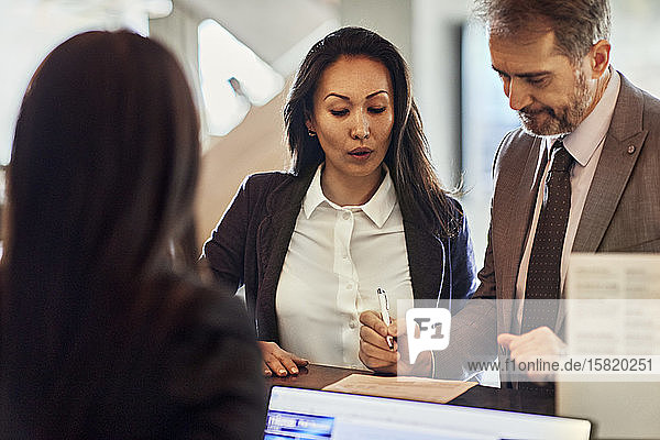 Business people checking in at reception desk in hotel