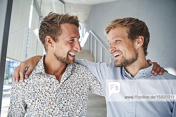 Porträt von zwei glücklichen jungen Geschäftsleuten  die sich umarmen