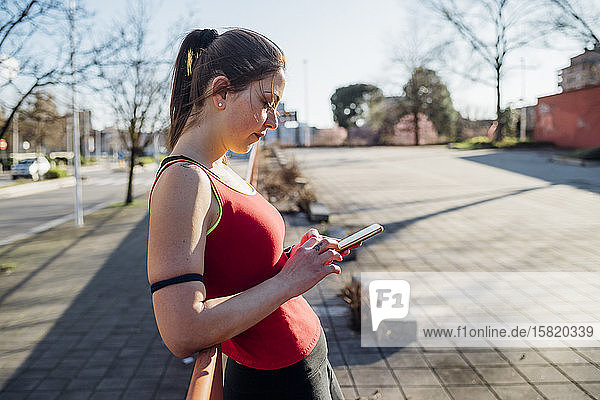 Sporty young woman using smartphone in the city