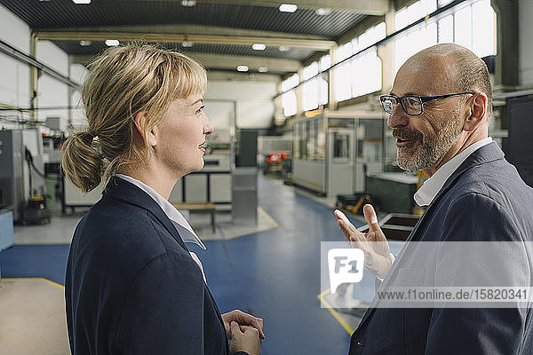 Businessman and businesswoman talking in a factory