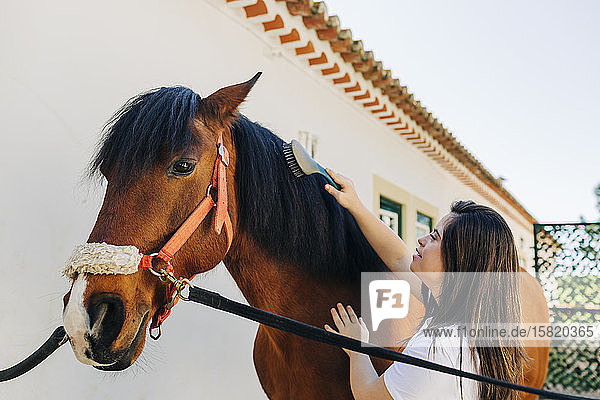 Teenager mit Down-Syndrom kümmert sich um Pferd und bereitet Pferd zum Reiten vor