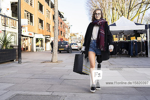 Portrait of confident young woman with leg prosthesis walking in the city