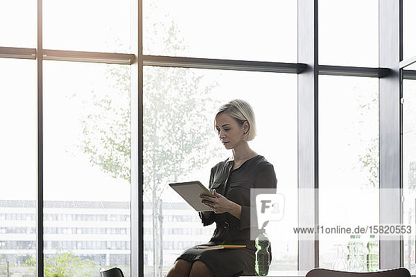 Businesswoman sitting on meeting table using digital tablet