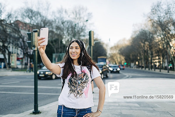 Young woman with headphones taking a selfie with her smartphone