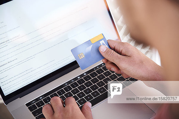 Mann mit Laptop und Kreditkarte in der Hand Nahaufnahme