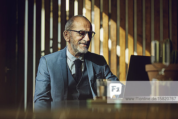 Leitender Geschäftsmann im nachhaltigen Büro sitzend  mit Laptop