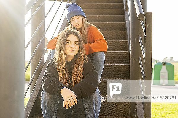 Porträt von zwei Mädchen im Teenageralter  die auf einer Treppe im Freien sitzen
