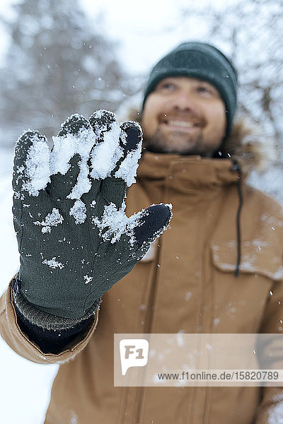 Man showing green glove with snow close-up