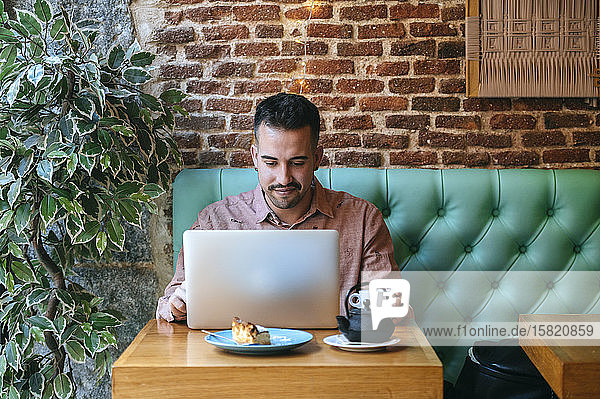 Mann in einem Café mit Laptop