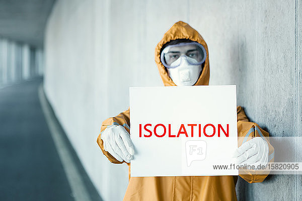 Porträt eines Mannes in Schutzkleidung mit einem Isolation -Schild