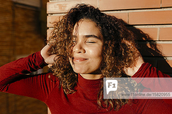 Portrait of young woman wearing red turtleneck pullover and enjoying sunlight