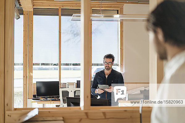 Businessman using tablet in wooden open-plan office