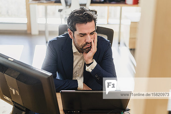 Frustrierter Geschäftsmann sitzt im Büro am Schreibtisch