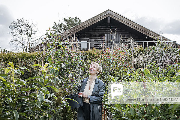 Lächelnde Frau mit Pflanztopf im Gartenzentrum