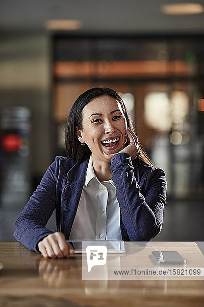 Porträt einer lachenden Geschäftsfrau bei Tisch