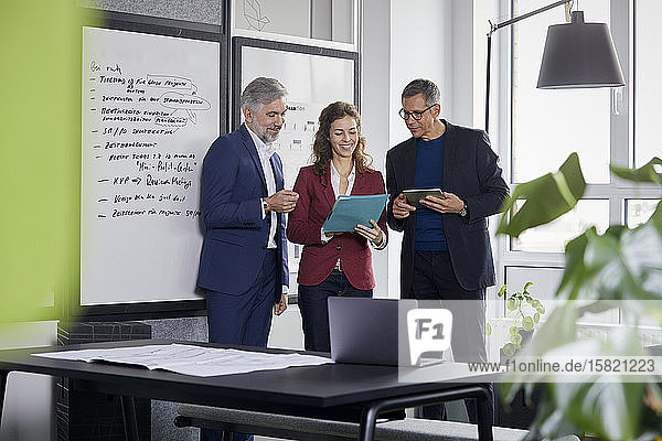 Zwei Geschäftsmänner und eine Geschäftsfrau arbeiten gemeinsam an einem Projekt im Amt