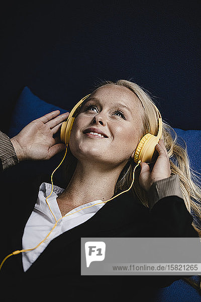 Porträt einer lächelnden jungen Geschäftsfrau  die mit Kopfhörern Musik hört