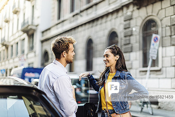 Young couple talking at a car in the city  Milan  Italy