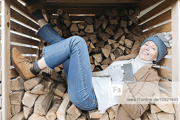 Bildnis einer glücklichen reifen Frau mit Axt auf Brennholz liegend