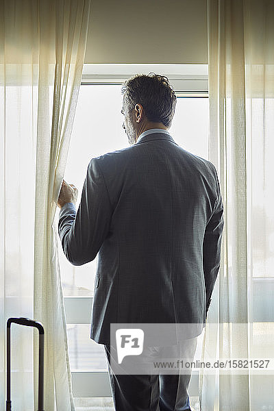 Geschäftsmann im Hotelzimmer der aus dem Fenster schaut