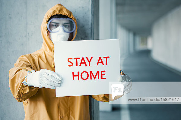 Porträt eines Mannes in Schutzkleidung mit einem Bleiben Sie zu Hause -Schild