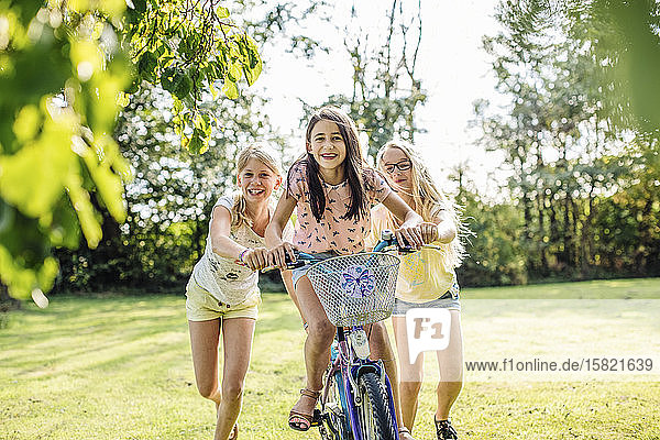 Happy girls riding bicycle in garden