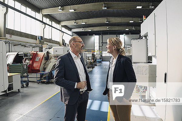 Happy businessman and businesswoman talking in a factory