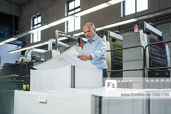 Geschäftsmann in einer Druckerei bei der Produktkontrolle