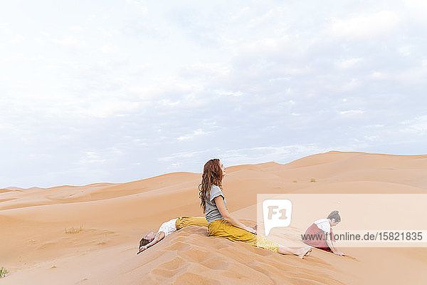 Three young women resting in sand dune in Sahara Desert  Merzouga  Morocco