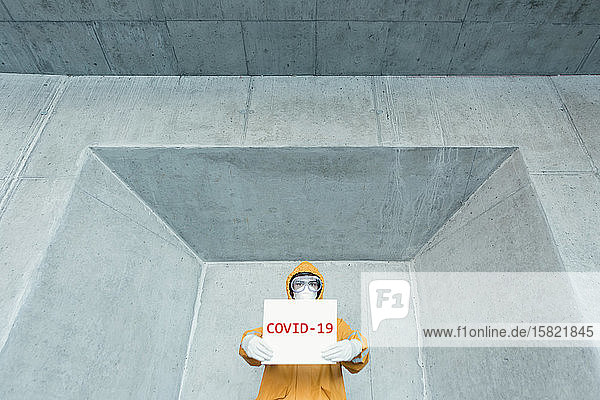 Porträt eines Mannes in Schutzkleidung mit dem Schild Covid 19