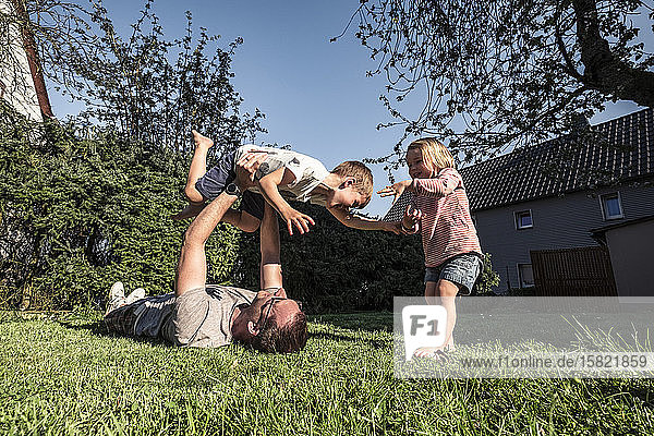 Vater spielt mit seinen beiden Kindern im Garten