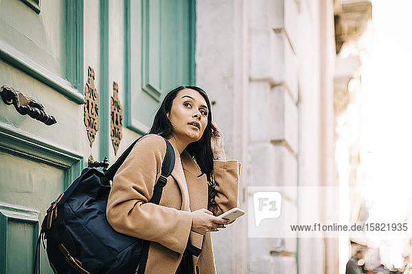 Porträt einer modischen jungen Frau mit Rucksack und Mobiltelefon  Lissabon  Portugal