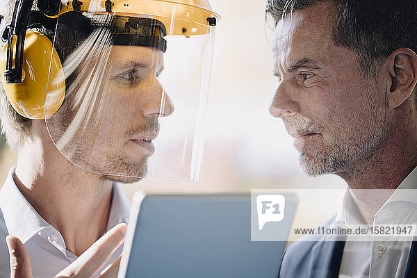 Businessman and man wearing safety helmet facing each other