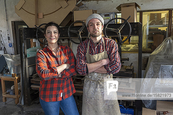 Porträt einer selbstbewussten Handwerkerin und eines Handwerkers in ihrer Werkstatt