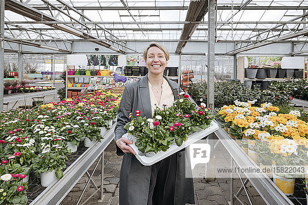 Smiling woman holding daisies in flower shop