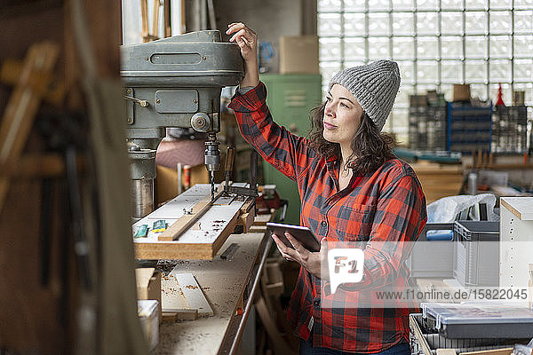 Craftswoman holding tablet in her workshop looking away