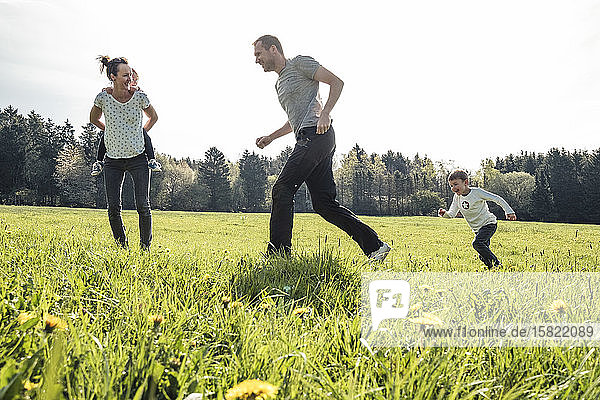 Familie mit zwei Kindern amüsiert sich im Frühling gemeinsam auf einer Wiese