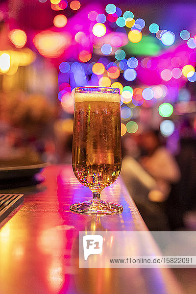 Full glass of beer standing on counter in nightclub