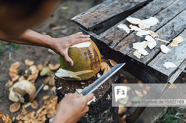 Schnittansicht eines jungen Mannes beim Öffnen der Kokosnuss  Insel Borneo  Malaysia