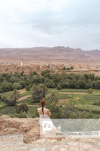 Back view of young womansitting on a rock looking at the city  Ouarzazate  Morocco