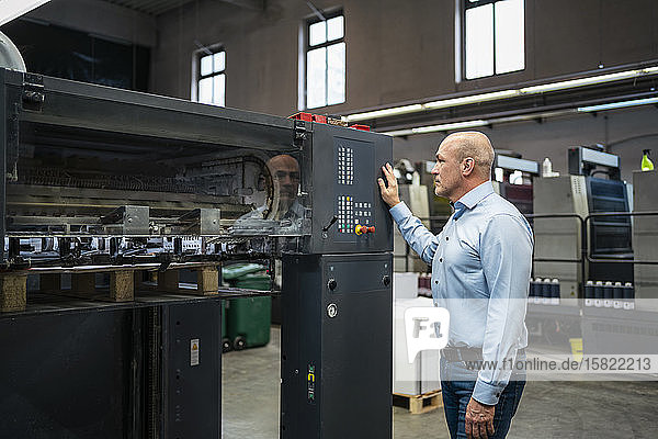 Geschäftsmann betrachtet eine Maschine in einer Fabrik