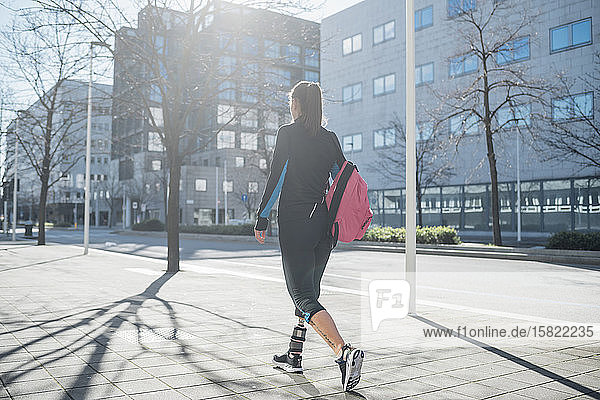 Sportliche junge Frau mit Beinprothese beim Spaziergang in der Stadt