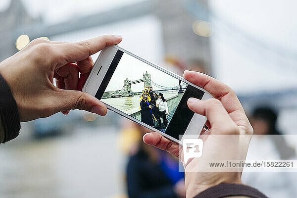 London  United Kingdom. A group of friends take pictures with a mobile phone in front of Tower Bridge