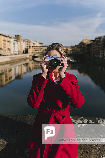 Young woman taking a picture on a bridge above river Arno  Florence  Italy