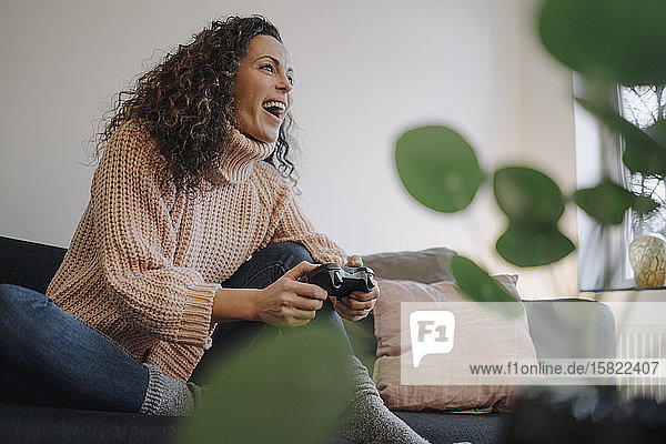 Frau sitzt auf dem Sofa  hat Spaß  spielt mit einer Spielkonsole